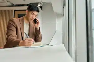 Jeune homme d'affaires au téléphone prenant des notes.