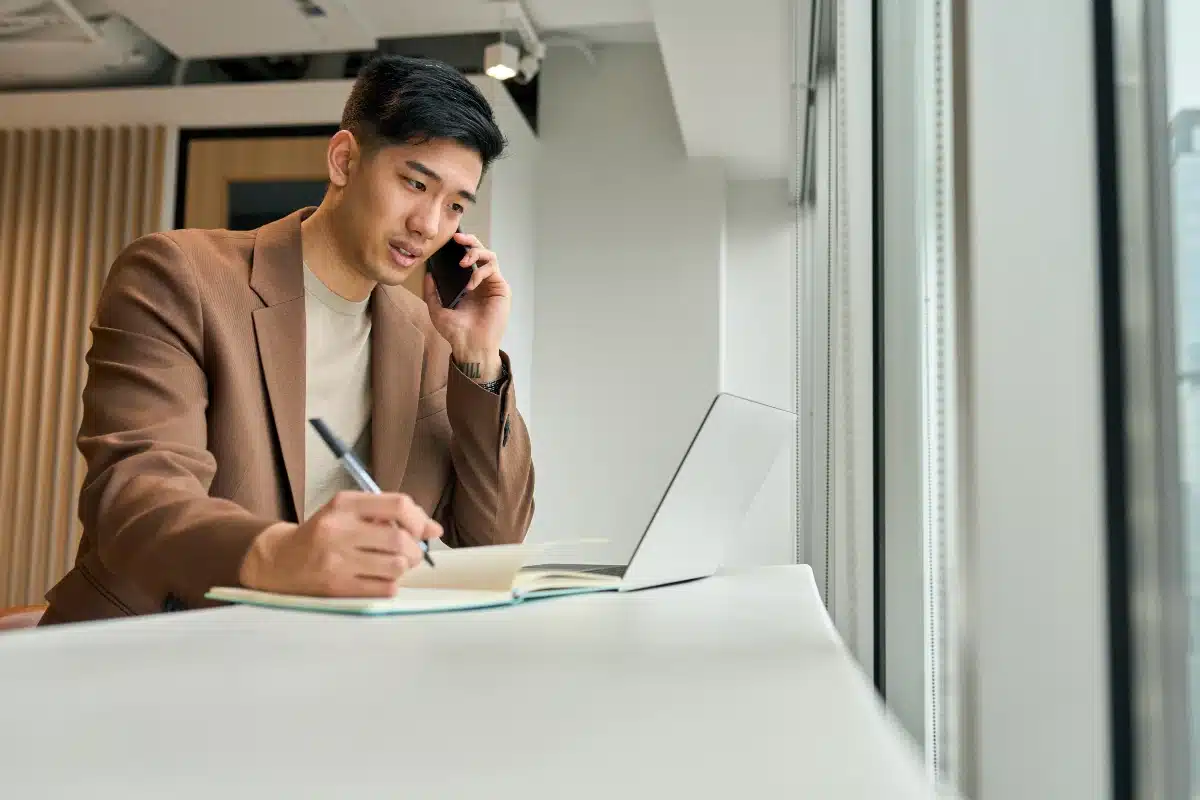 Jeune homme d'affaires au téléphone prenant des notes.